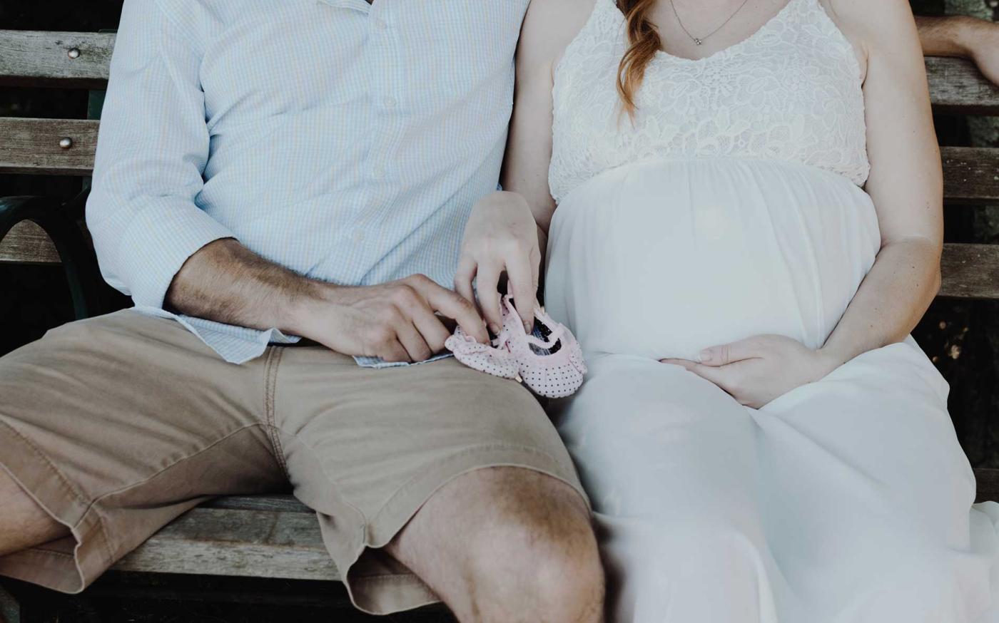 Man and pregnant wife sitting on bench.