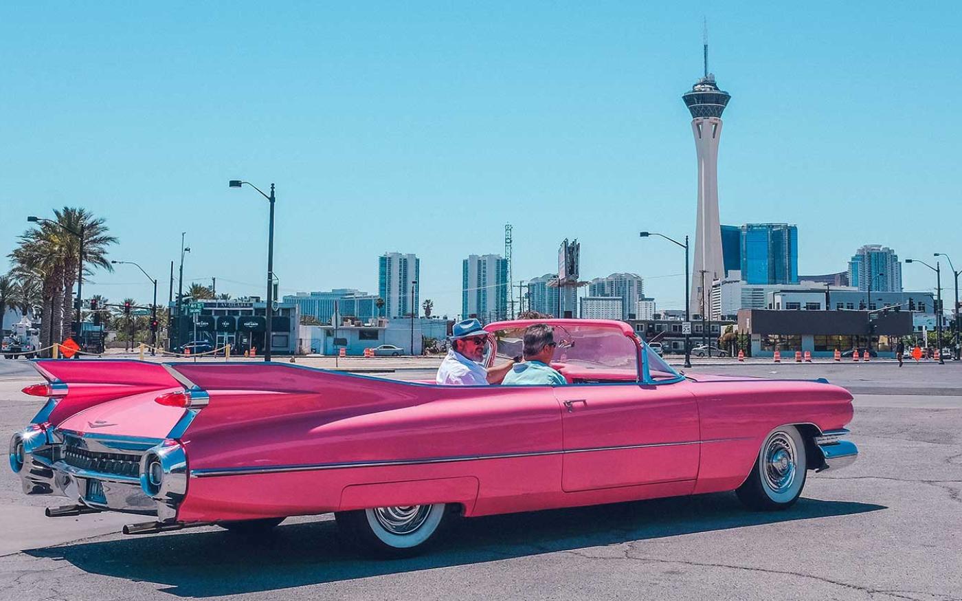 Old school car with city view in background.