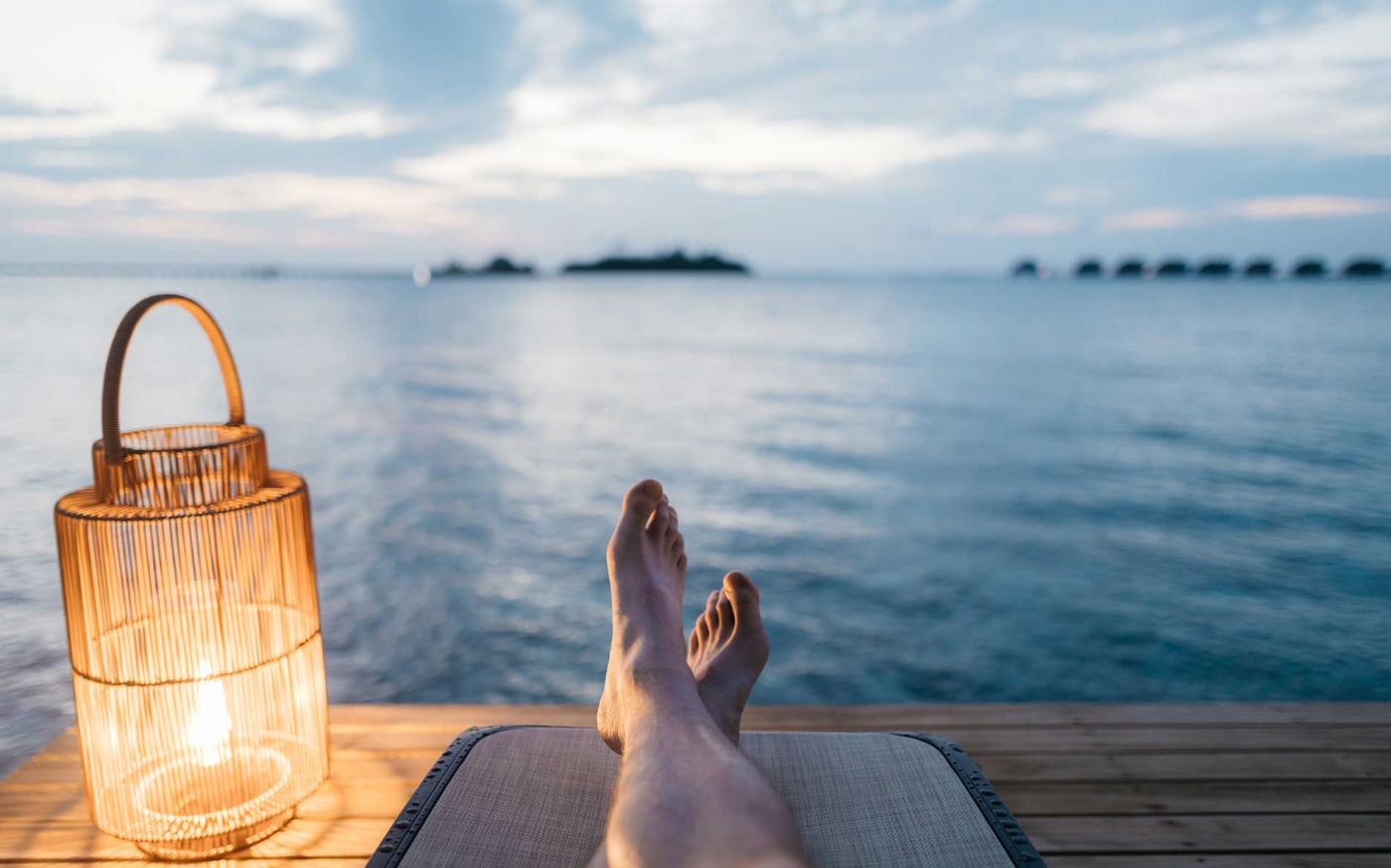 Person sitting on dock staring out at water.